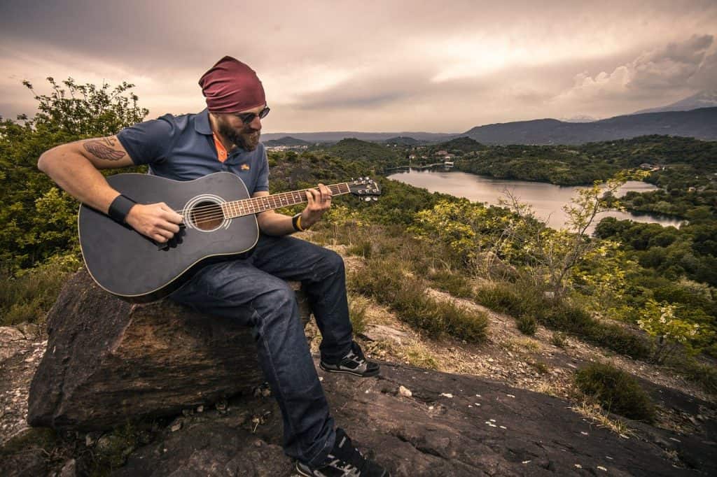 Guy playing guitar sitting on a rock