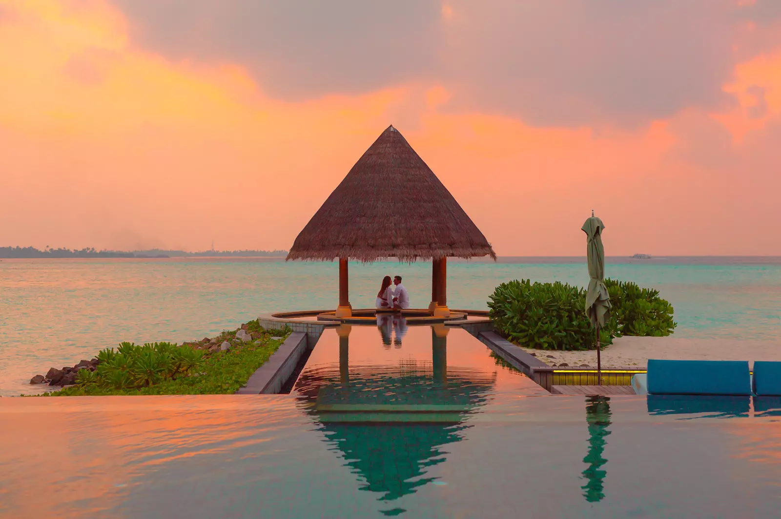 Luxury honeymoon, couple under hut beside sea and infinity pool