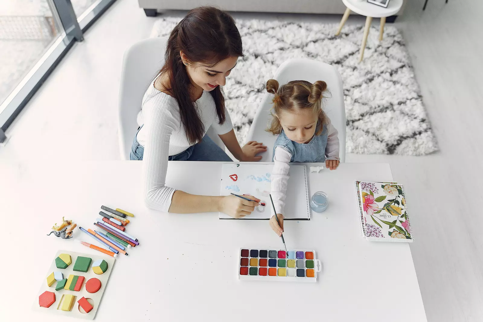 Kid and her mum are painting together at their home