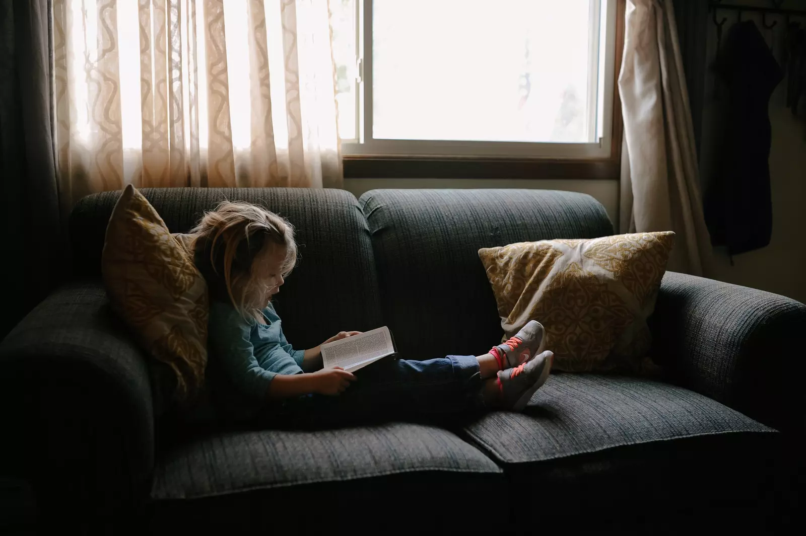 Kid reading a book on a sofa