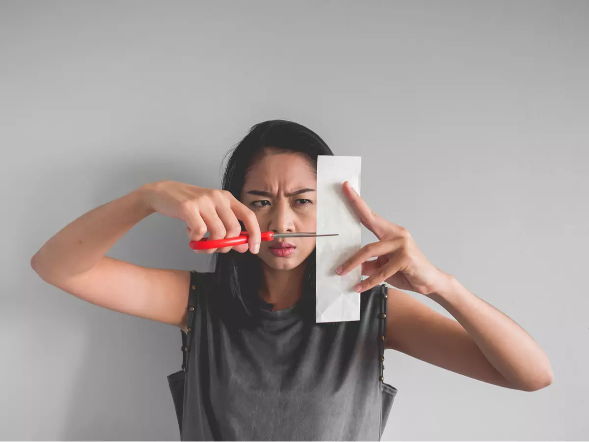 Woman cutting a receipt in half with scissors.