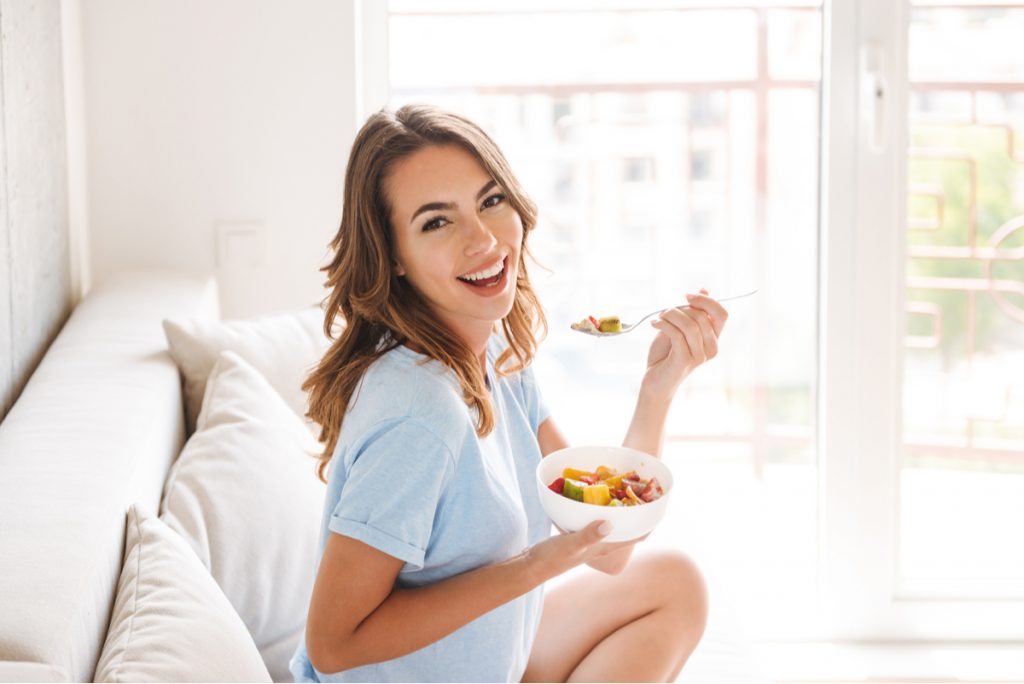 Woman eating healthy food at home on the couch.