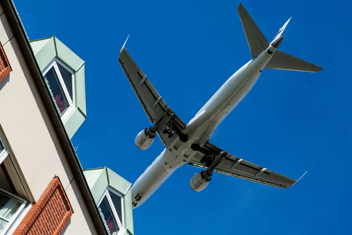 Plane flies over a house.