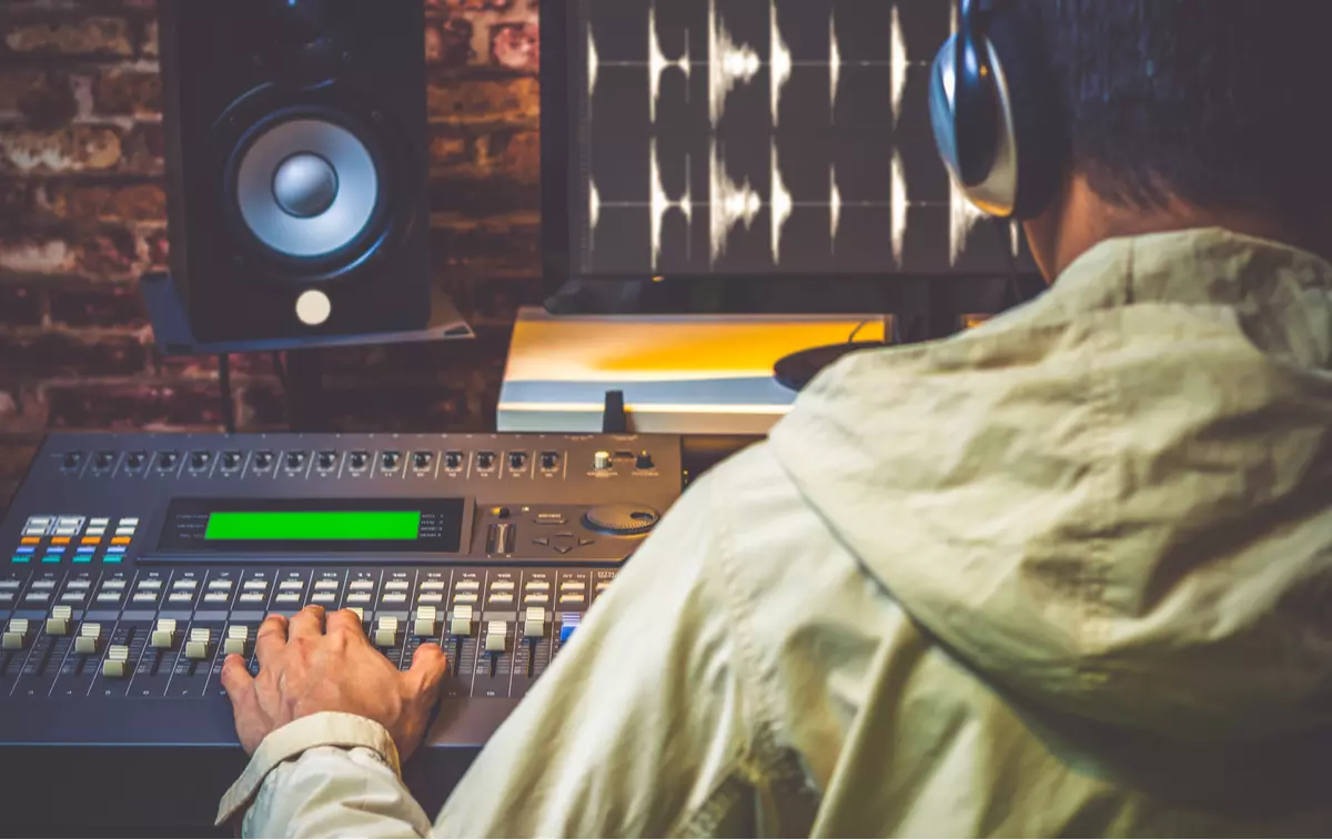 Man editing music on a soundboard and computer.