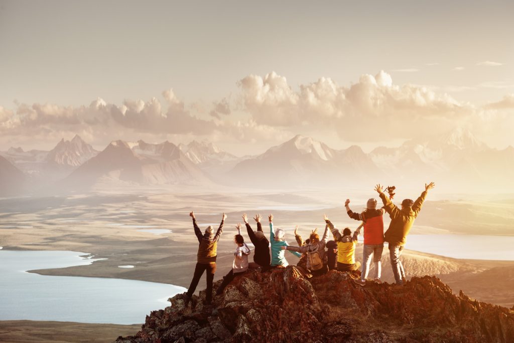 Group of travelers looking at the sunset from the top of a hill or mountain.