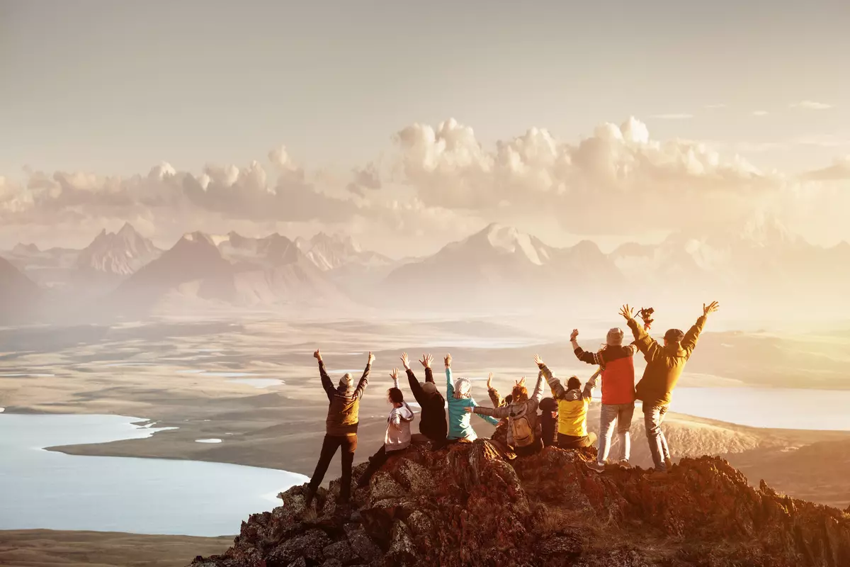 Group of travelers looking at the sunset from the top of a hill or mountain.