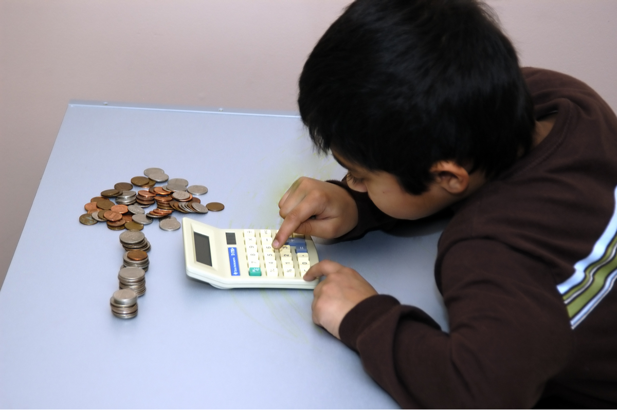 Boy counting coins using a calculator.
