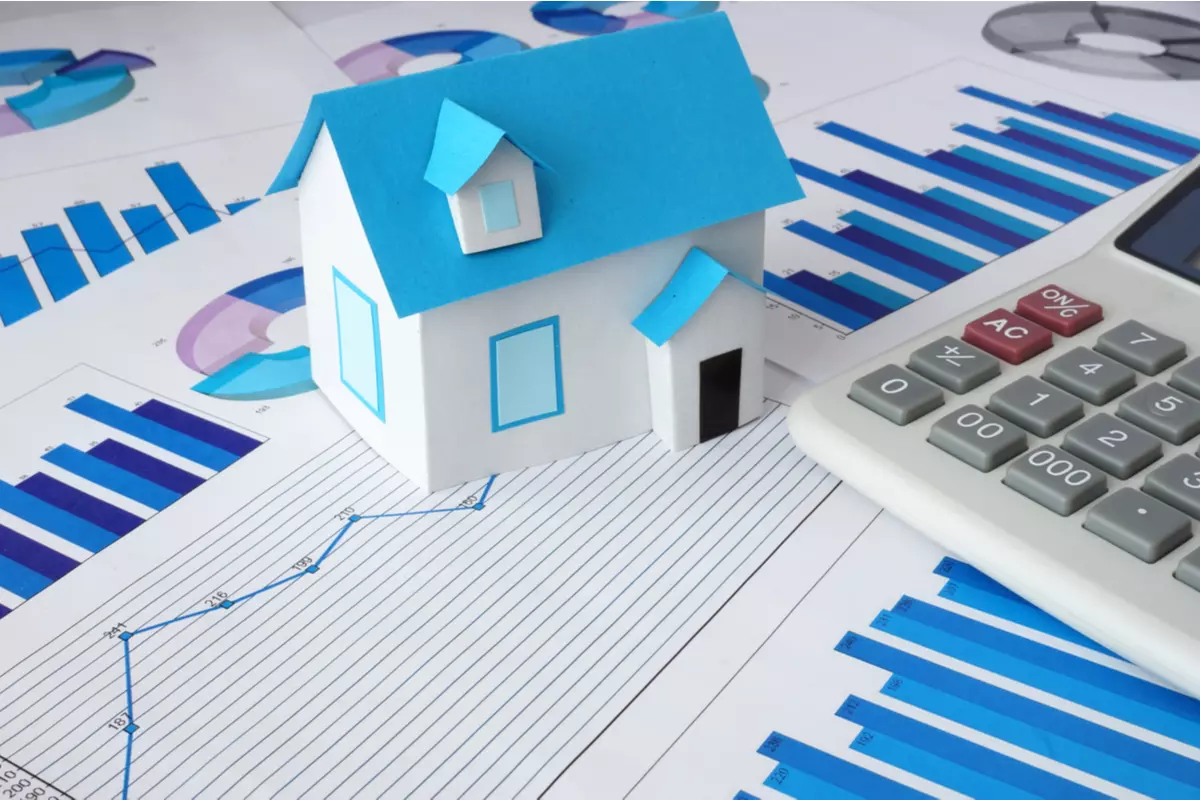 A model house sitting next to a calculator and charts.