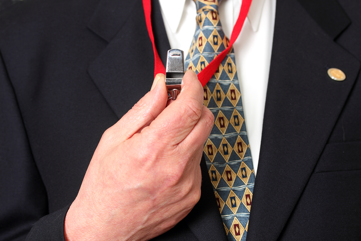 A businessman holding a whistle.