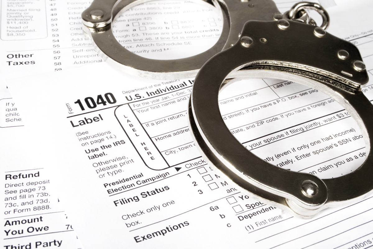 Handcuffs over an IRS fraud reporting form 