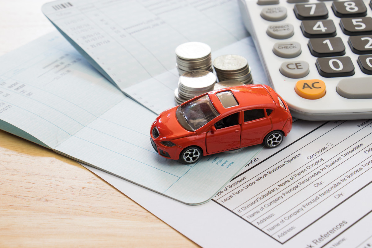 A small model car on top of car insurance forms. 