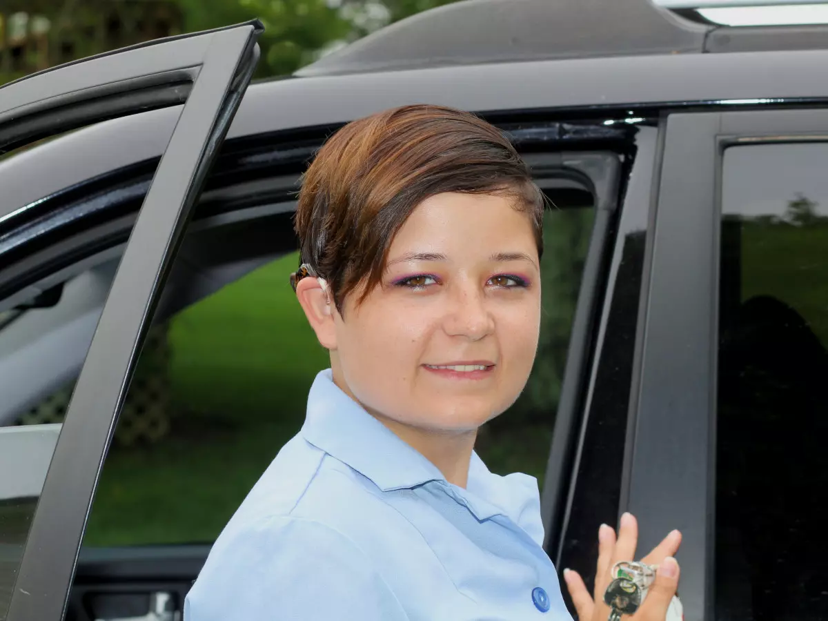 A deaf person standing next to a car