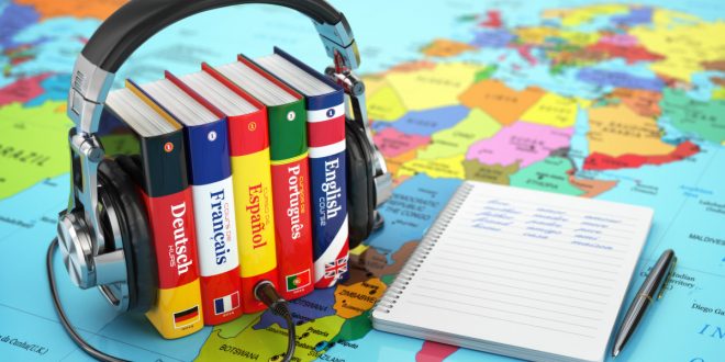 A world map with books of languages and earphones