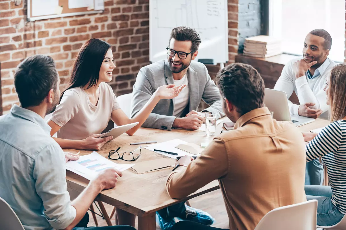 A team of office workers displaying social wellness at a meeting.