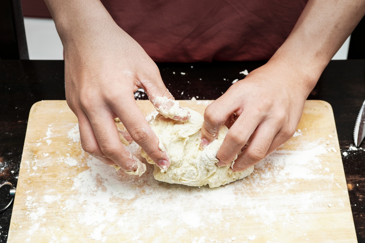 A bakery owner kneading dough. 