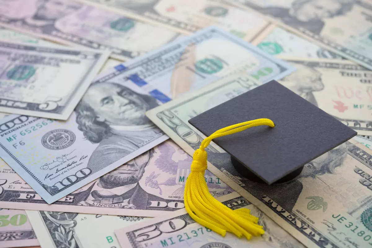 A graduation cap atop a pile of money.