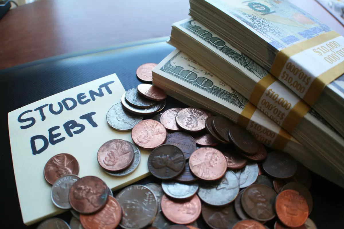 A sticky note with the words "student debt" next to a pile of cash. 