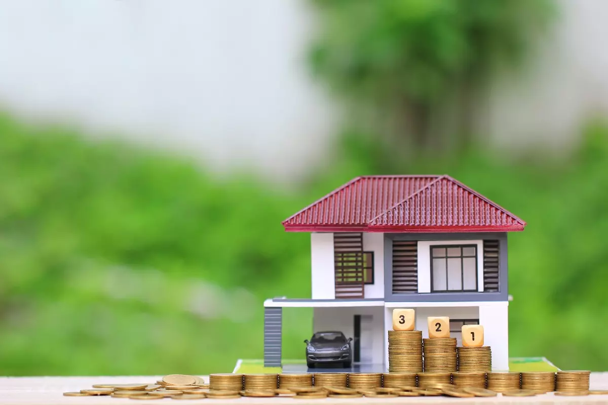 Toy house and car with coin stacks.