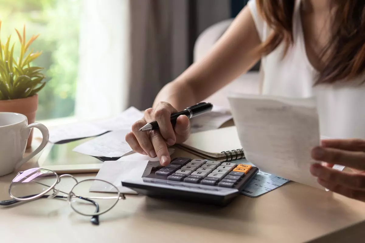 Young adult using calculator to budget finances.