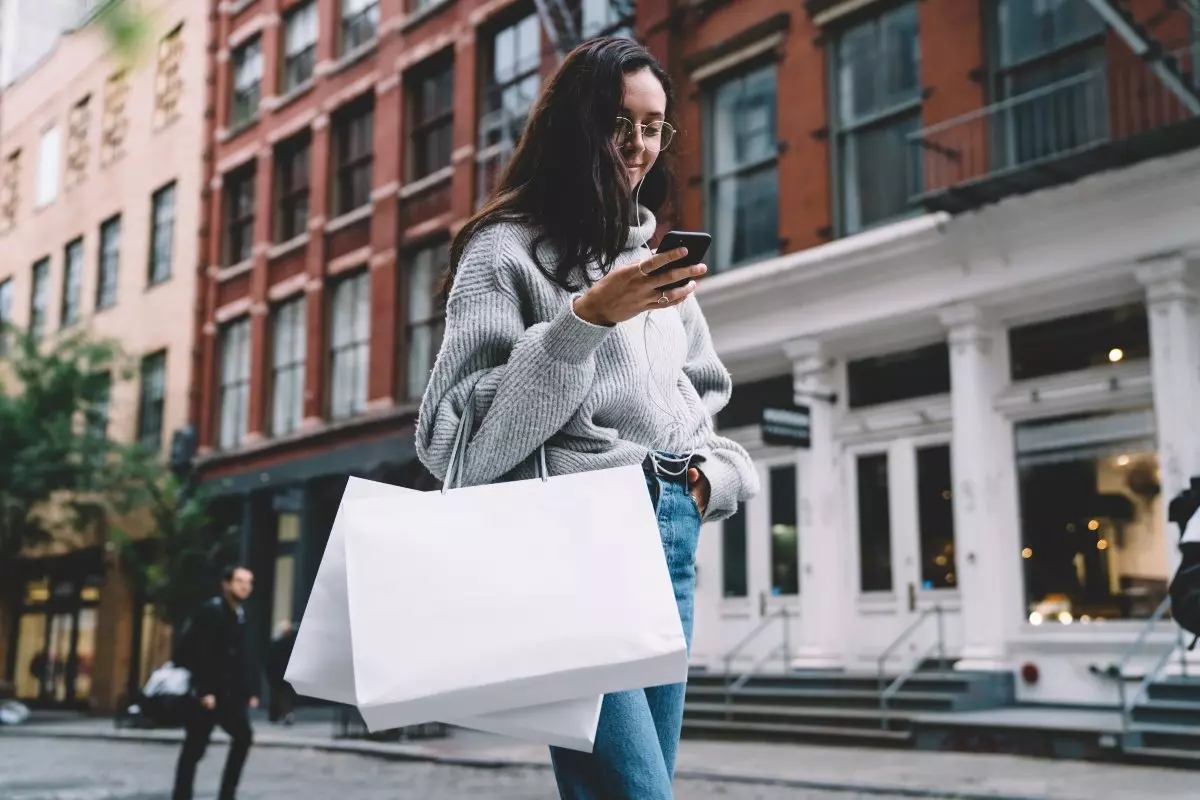 Young adult holding shopping bags on the street.