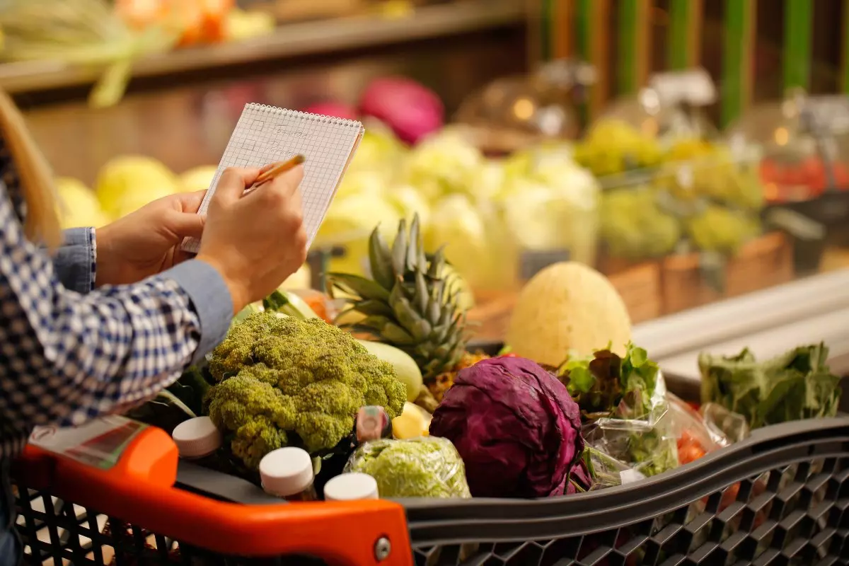 An individual using a grocery shopping list to prevent overspending.