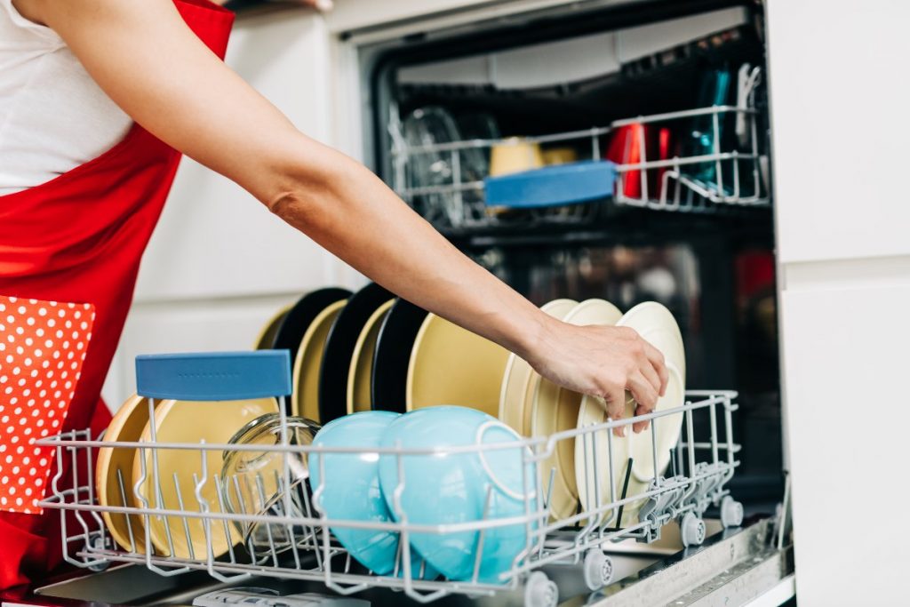 Individual placing dishes in dishwasher.