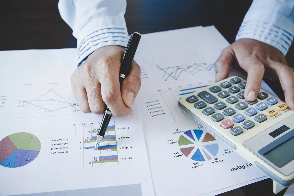 Close up on financial reports and actuary using calculator.