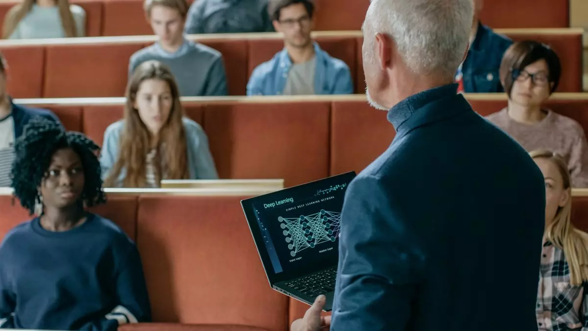 University professor holding laptop and lecturing to class