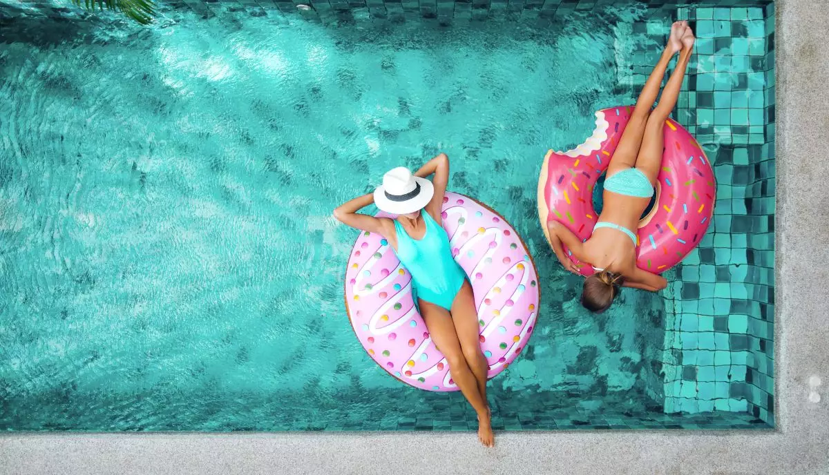 Two young adults floating in pool 