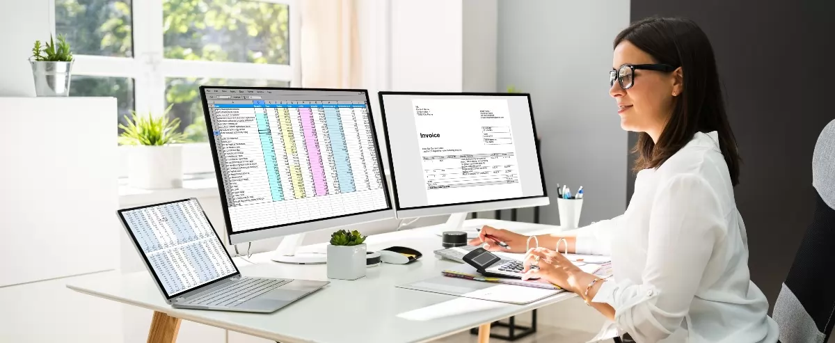 Businessperson invoicing on computers and laptop.