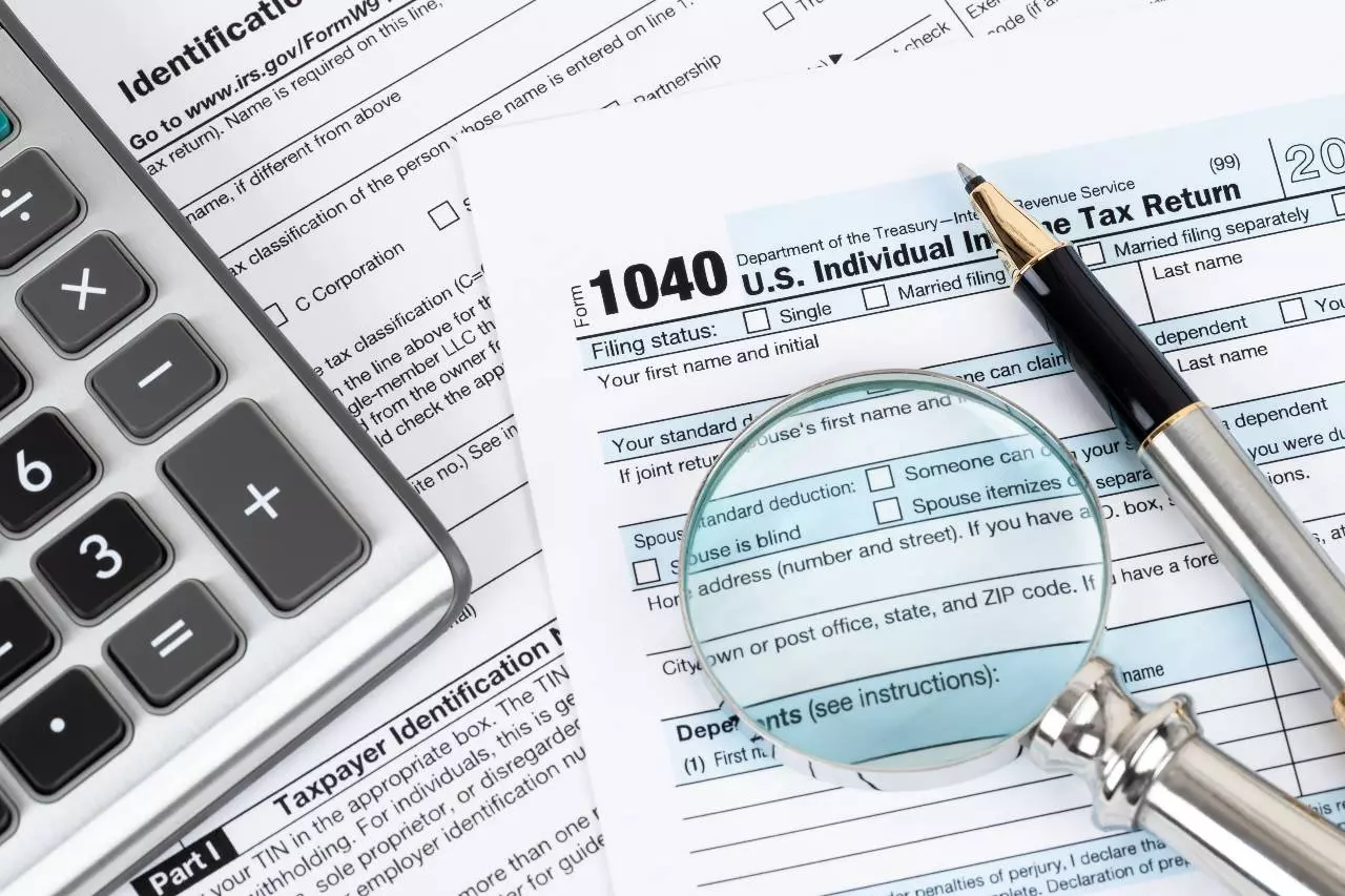 Close up on tax return paperwork, pen, and magnifying glass