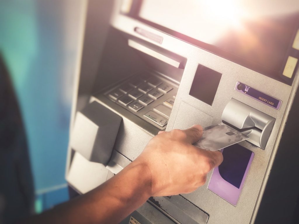 Close up on individual inserting card into ATM