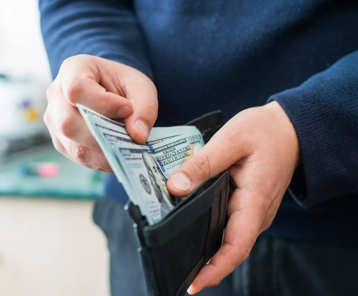 Close up on man pulling out residual income from wallet 