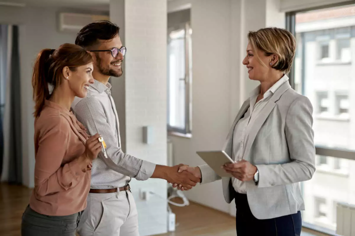 Home buyers shaking hands with real estate agent 