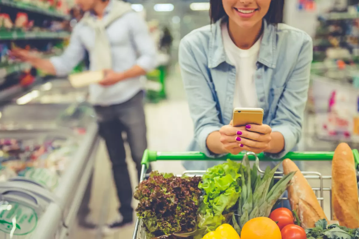 Young adult pushing full shopping cart in grocery store