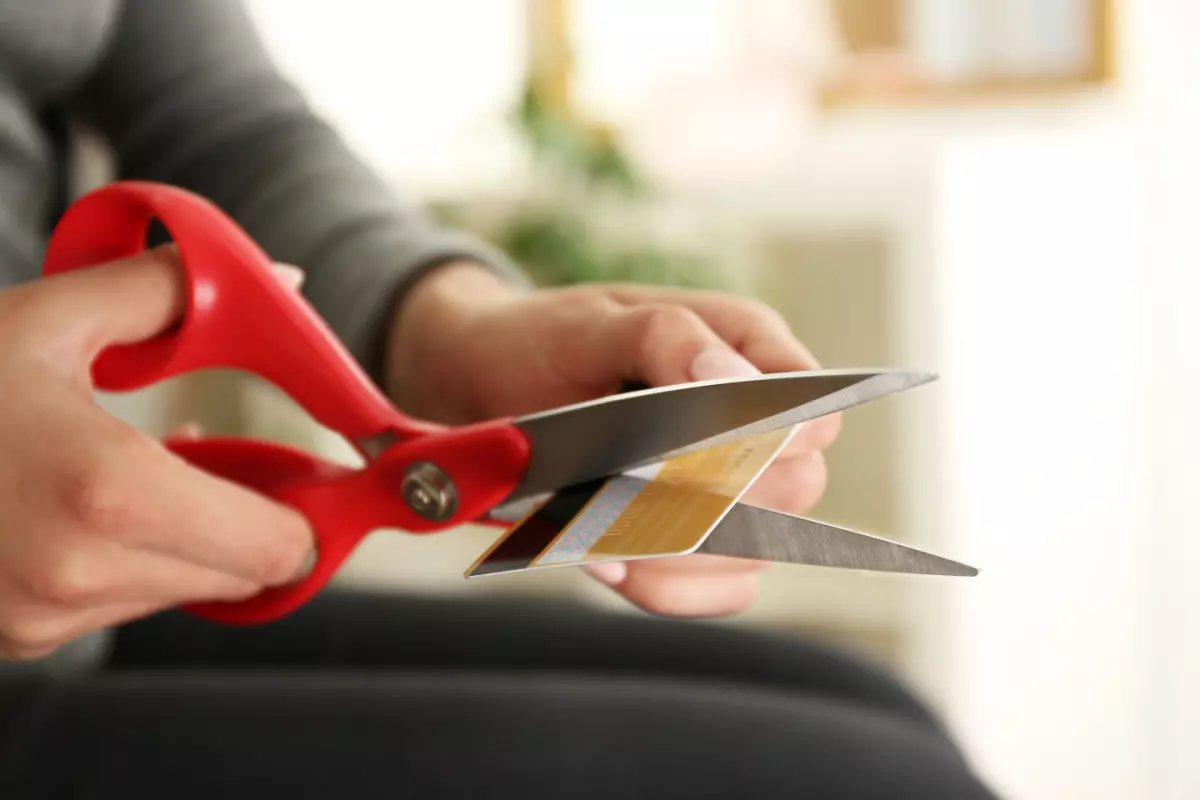 Close up on cardholder cutting credit card with scissors 